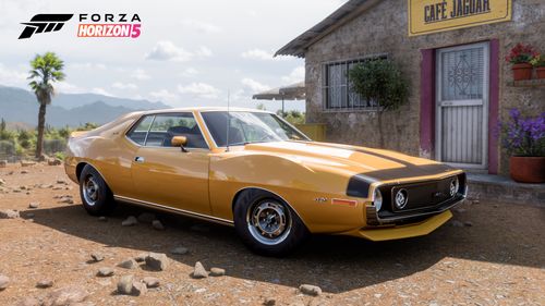A yellow AMC Javelin AMX is posed in front of a cafe.