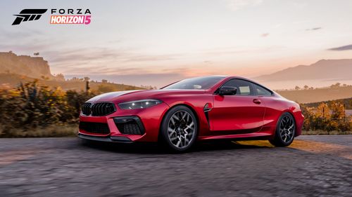 A red BMW M8 Competition is posed in front in front of a vista.