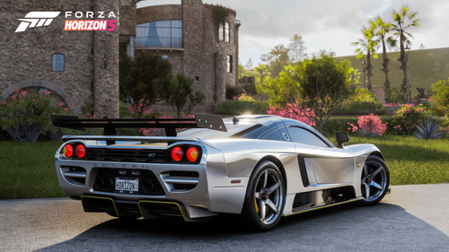 A grey Saleen S7 parked outside of a building in front of a garden