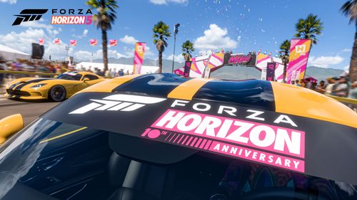 A zoom in of the Forza Horizon 10-Year Anniversary logo painted on the windscreen cover of the 2013 Dodge SRT Viper GTS Anniversary Edition as it drives through the Horizon Festival beside another black and yellow SRT Viper.