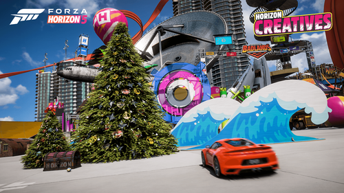 An orange car parked in front of large props featuring a holiday tree and a wave in front of a tall building