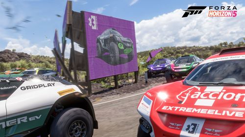 Several Extreme E race cars drive by a purple Extreme E billboard in Mexico, indicating a nearby Extreme E Seasonal Championship.