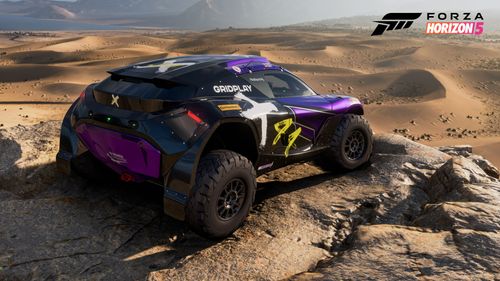 The 2022 Extreme E #44 X44 adorned in a black and purple team livery watches over the sand desert while parked on a large rock.