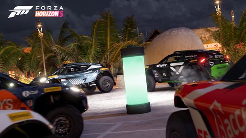 Four Extreme E off-road race cars find a hidden "Battery" collectible in a Mexican seaside town at dusk.