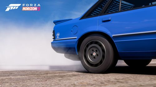 The rear tires of a blue HDT VK Commodore Cgroup A spin up smoke in FH5.