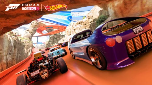 A group of Hot Wheels cars, with a purple Deora most prominent, pass under an arch and race away from the camera on orange track in the rocky canyon biome. Blue and orange tracks are visible in the background. 