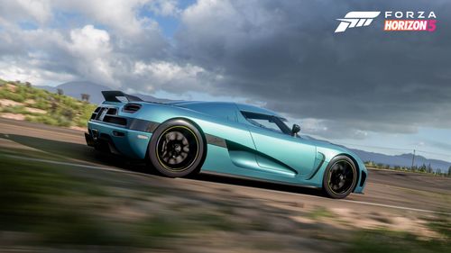A side view of the metallic blue 2011 Koenigsegg Agera as it drives through the living desert.