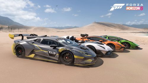 Four hypercars lined up in the sand in front of dunes on a clear day