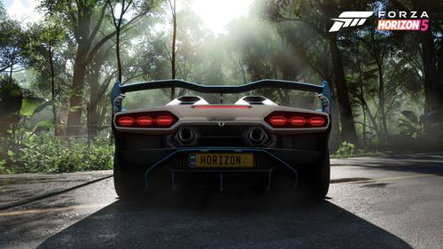 The back of a Lamborghini with its rear lights on stading against the sun casting a shadow on the ground