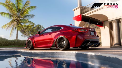 A red Lexus RC F with a Rocket Bunny body kit parked by a house with a pool reflecting the car.