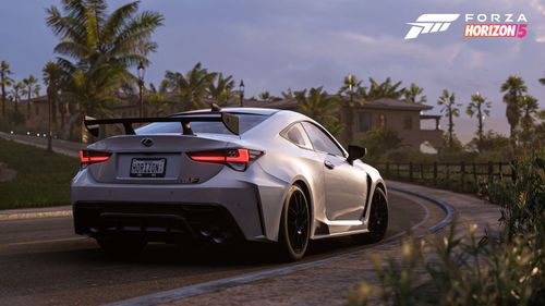 A white Lexus RC F Track Edition parked by a cream colored villa after sunset.