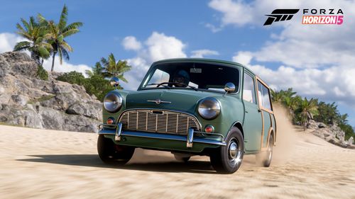 A green 1965 Morris Mini-Traveller drives through a sandy beach.