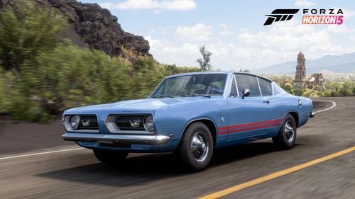 A blue Plymouth Barracuda Formula S drives along a road by green shrubbery and large rocks.