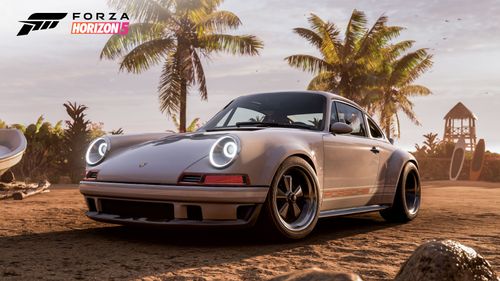 A silver Porsche 911 parked on a sandy beach in front of palm trees.