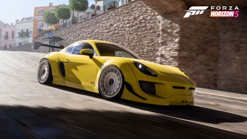 A yellow Porsche Cayman GTS with a Rocket Bunny body kit drives into a tunnel in Guanajuato.