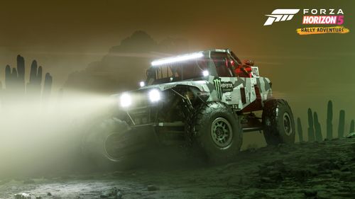 A Casey Currie Motorsports buggy with its headlights turned on is seen parked on top of gravel in an eerie setting with a green tint and orange aura. 