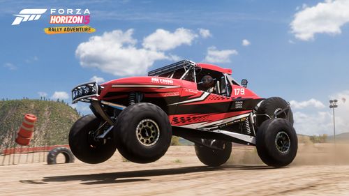 A red and black Jimco Hammerhead buggy pulls a wheelie on a dirt trail.