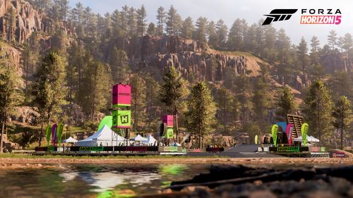 A side view of the Horizon Colorado Festival Outpost surrounded by trees and large rocks in the vast canyon region.