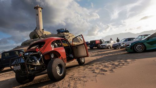 Няколко коли, паркирани в пясъчна зона под лека кула