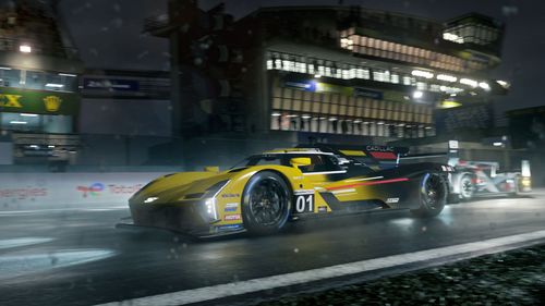2023 Cadillac Racing V-Series.R #01 in yellow racing at a circuit at night time.  The left side of the car is fully visible as the car races, at speed, while facing to the left of the image, with headlights illuminating the road ahead and trackside.