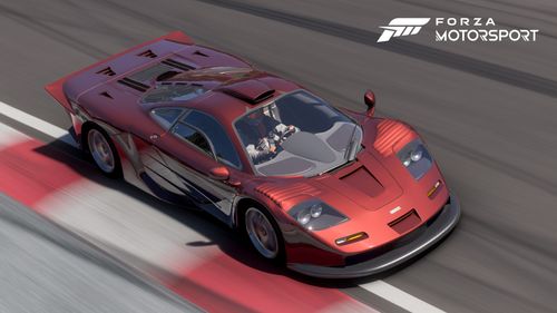 Orange-red McLaren F1 rushing through a track touching the border of the curb